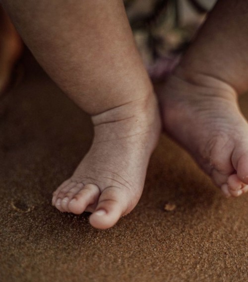 The feet of a baby on a sandy background.