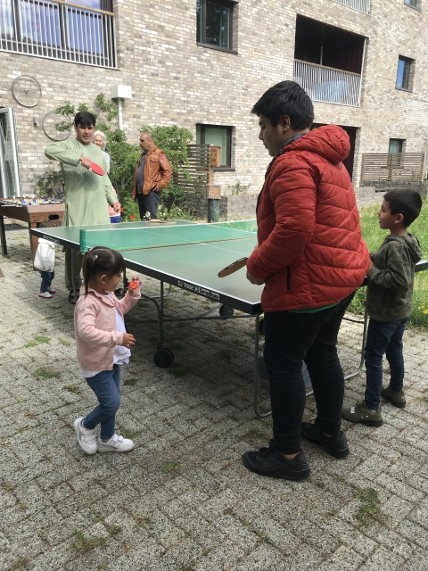 A group of men and children play table tennis in a driveway